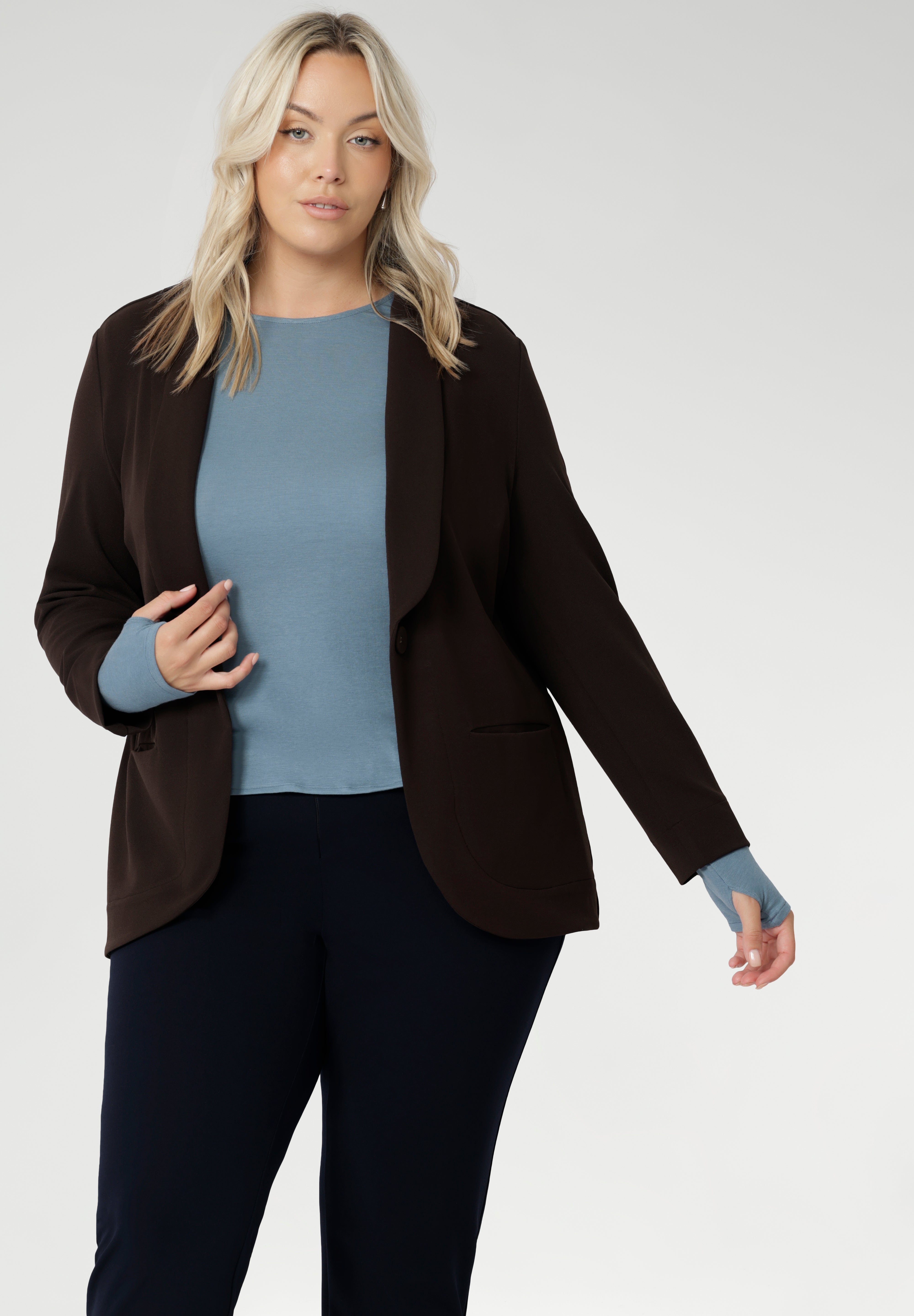 Featuring a classic round neckline and long sleeves, it’s designed with comfort in mind — offering generous stretch and a smooth, breathable feel, without the itch of traditional merino. Size 18 model wears cocoa Merit Blazer over wool top, paired with womens navy work pants.
