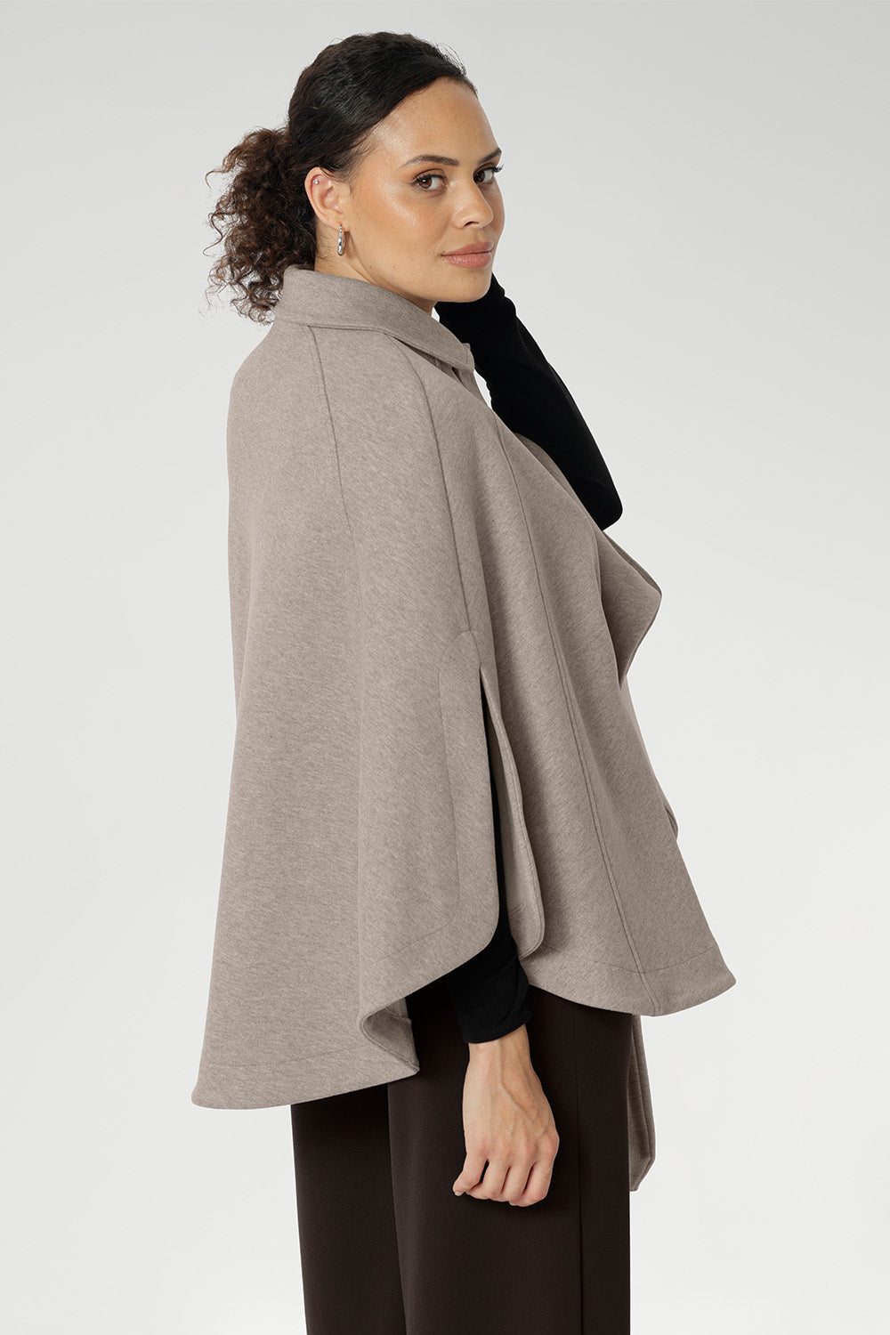 The tailored silhouette is enhanced with three front buttons that fasten cleanly across the chest, while a cleverly designed waistband wraps around the back and threads through discreet loop holes to cinch the waist and define your shape. Arm slits crafted into the sides allow for natural movement and create a graceful flare as you walk, adding fluidity and ease to every step.