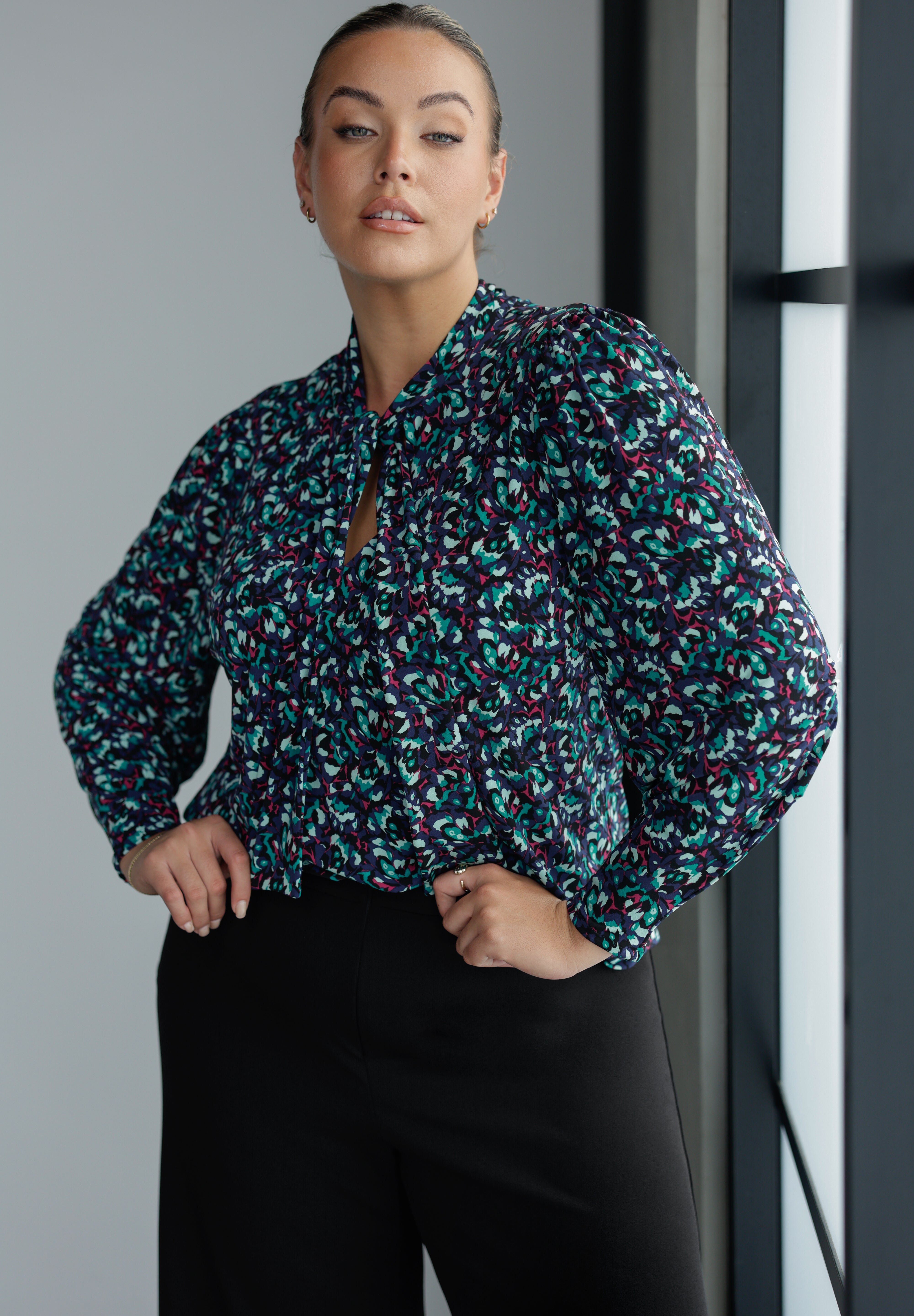 The Celine Top brings refined drama to cool-weather dressing, blending softness, structure, and statement detail in one beautifully cut piece. With its elegant V-neckline and flowing attached neck ties, this blouse offers effortless sophistication, while subtle tailored tucks at the back create a graceful shape that moves easily with the body.