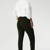 Back view image of The Corbin Pant in Olive worn with lightweight blouse and black loafers. The pants are designed with angled front pockets, giving them a modern touch, while the back darts ensure a tailored fit that contours to the shape of the body.