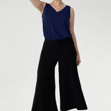 A size 10 woman wears black wide-leg pants and navy top. Cropped in length, the black pants have a smooth waistband, side pockets and are pull-on pants made in stretch jersey. Made in Australia, the pants are size inclusive in sizes 8 - 24.