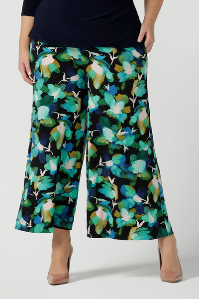 Close up of a size 18 woman wearing the Dany culotte in Canopy, a full leg culotte with a canopy print. A bold green colour splatter print. Styled back with pink heels and a navy wrap top. Made in Australia for women size 8 - 24.