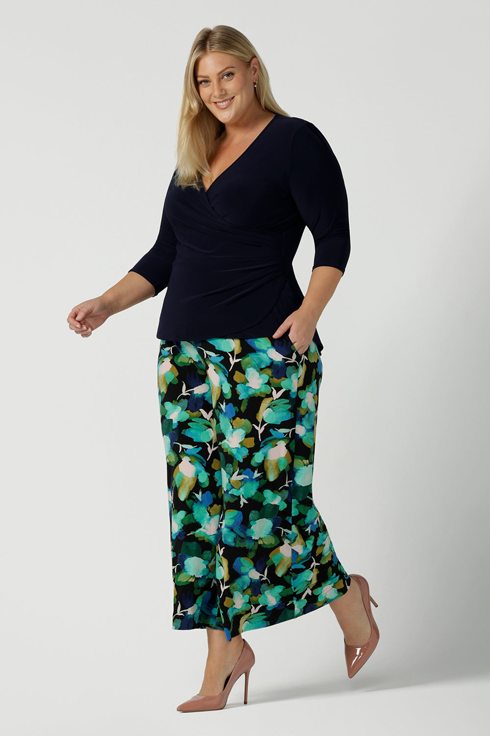 Size 18 woman wears the Dany culotte in Canopy, a full leg culotte with a canopy print. A bold green colour splatter print. Styled back with pink heels and a navy wrap top. Made in Australia for women size 8 - 24.