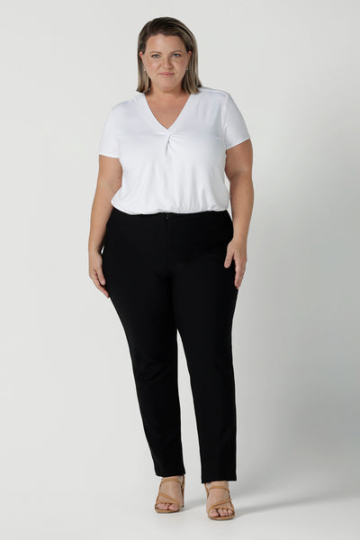 A plus size 18 woman wears slim leg, black pants by Australian and New Zealand women's clothing brand, L&F. These comfortable work pants are worn with a white Emily top in bamboo. Made in Australia for women size 8 - 24.