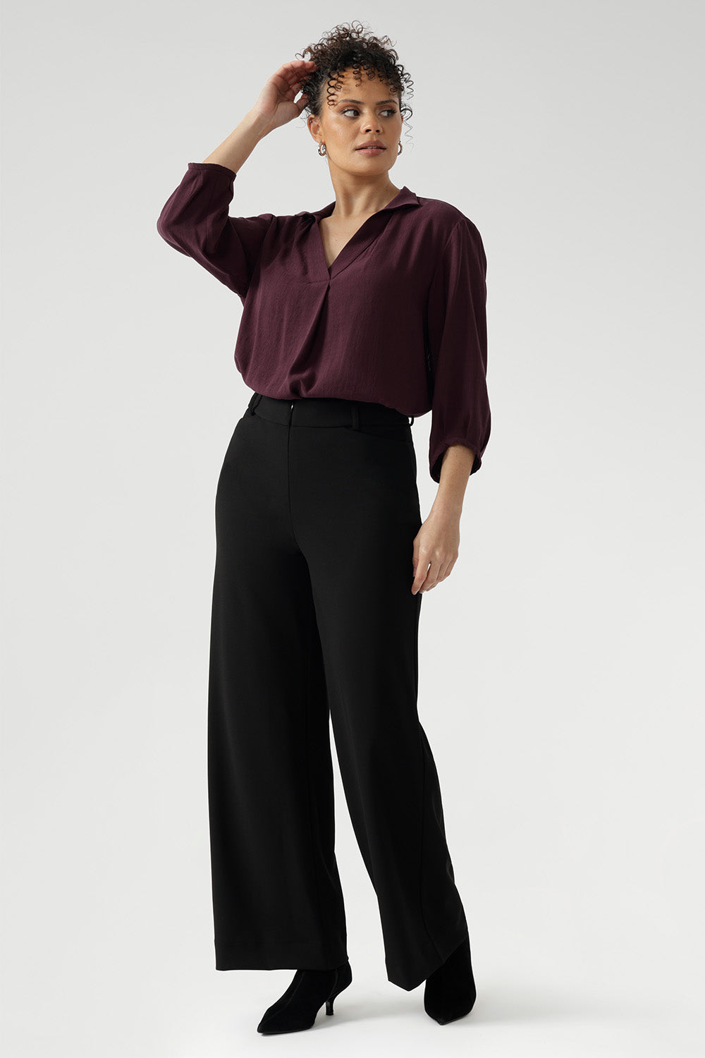 Full body back image of tall woman wearing. Black work wear pants. Easy care fabric used to craft pants is scuba crepe. Off duty pants provide breathable stretch and comfort. Australia Made for woman in Australia and New Zealand. Leina & Fleur is a woman’s clothing brand that has sizes ranging from 8 to 24 including plus sizes and petite sizes.