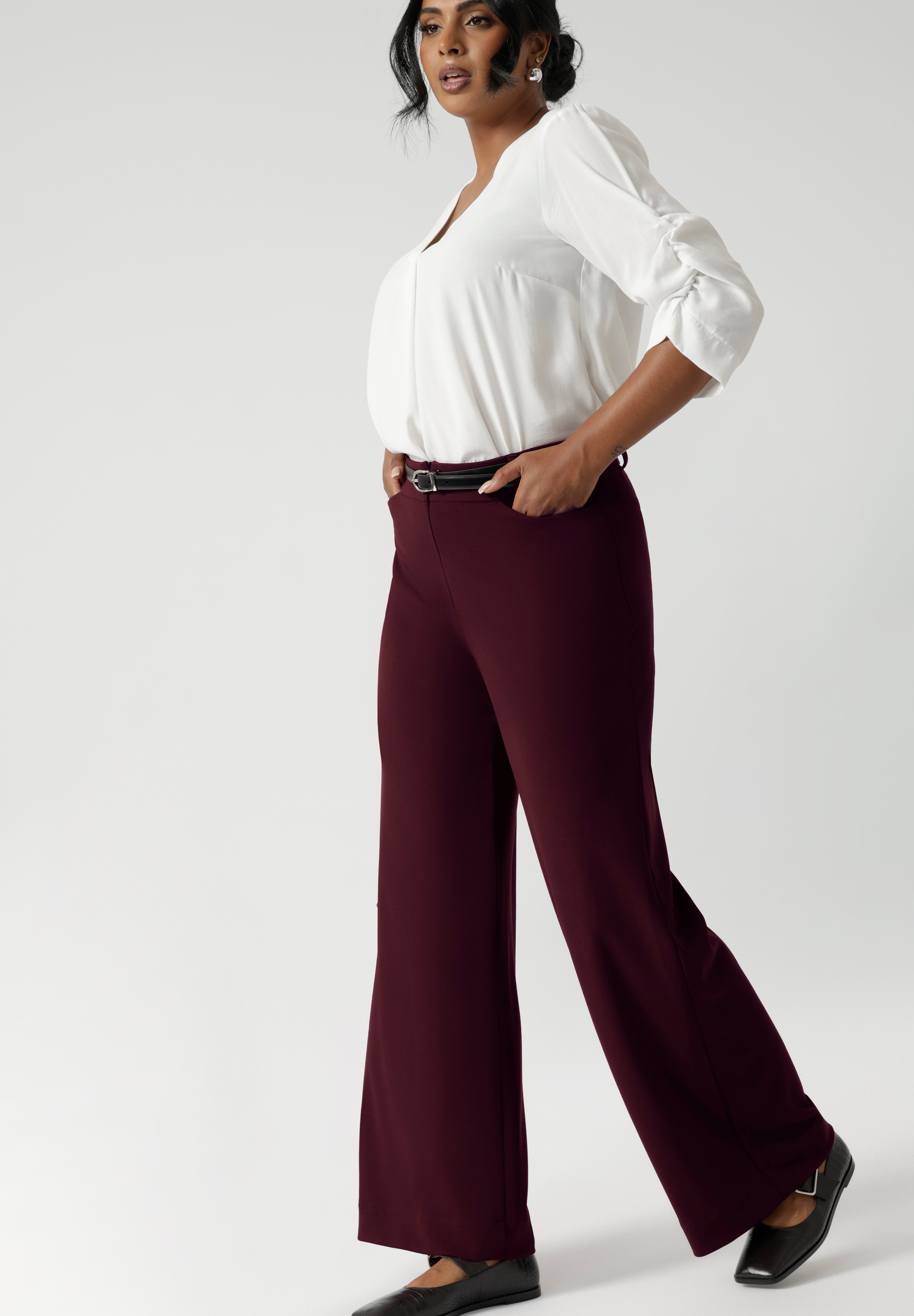 The high-rise design offers a flattering and comfortable fit, with a waistband that includes belt loops for added styling options. The invisible front zip with an internal button ensures a sleek, streamlined look while providing a secure fit.