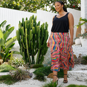 A size 18, curvy woman wears a jersey maxi skirt in kaleidoscope print with black cami top, all made in Australia by women's clothing brand, Leina & Fleur, as inspiration of summer outfits to wear for summer events and outings.