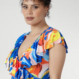 In cool-touch slinky jersey, the Elle Maxi Wrap Dress in Summer Bliss offers effortless elegance. The wrap silhouette with tie waist flatters every shape, while a raw edge frill and abstract floral print add a modern touch. Complete with pockets and a double-layered back for comfort — ideal for summer parties and relaxed days.
