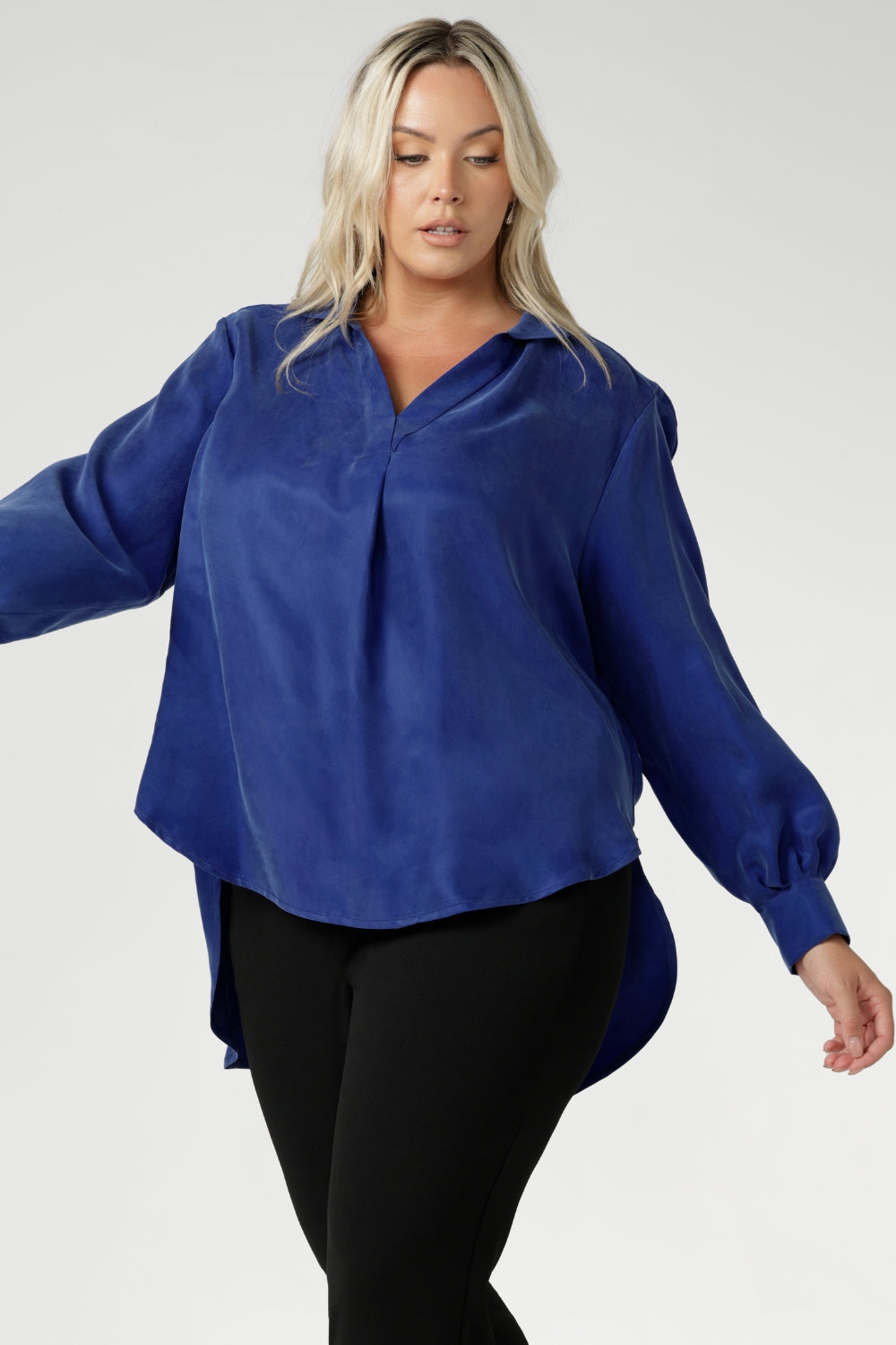 Plus size woman wears oversized blouse made from suede touch Tencel fabric. Workwear shirt features a collared V-neckline, cuffed sleeves and shirttail hemline that sits longer at the back. Woman's workwear clothing proudly made in Australia in sizes 8-24.