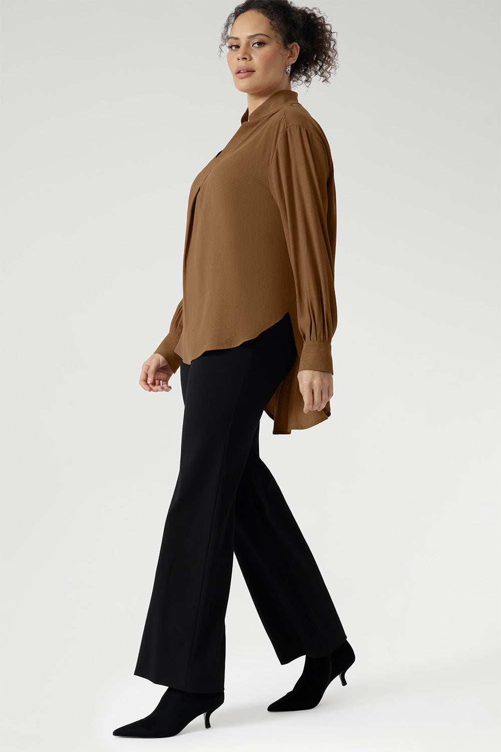 The full-length sleeves are finished with clean cuffs and covered buttons — an understated touch that elevates the look. A gently curved shirttail hem sits longer at the back, offering balanced proportions and flattering coverage.