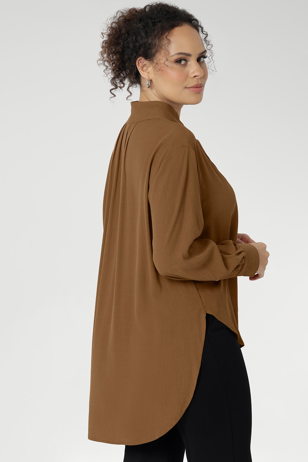 Plus size woman wears lightweight, easy to wear shirt that holds its shape without stretch. In the warm neutral shade of Nuthatch, it brings subtle sophistication to everyday dressing. The full-length sleeves are finished with clean cuffs and covered buttons — an understated touch that elevates the look. A gently curved shirttail hem sits longer at the back, offering balanced proportions and flattering coverage. Available in size 8-24.