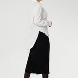 Back view of a size 10 woman wears the Ellis shirt in Vanilla tencel, a high quality made in Australia womens shirt made in breathable tencel. Inclusive size range 8-24 and made in Australia. Styled with black midi tube skirt and brown boots.