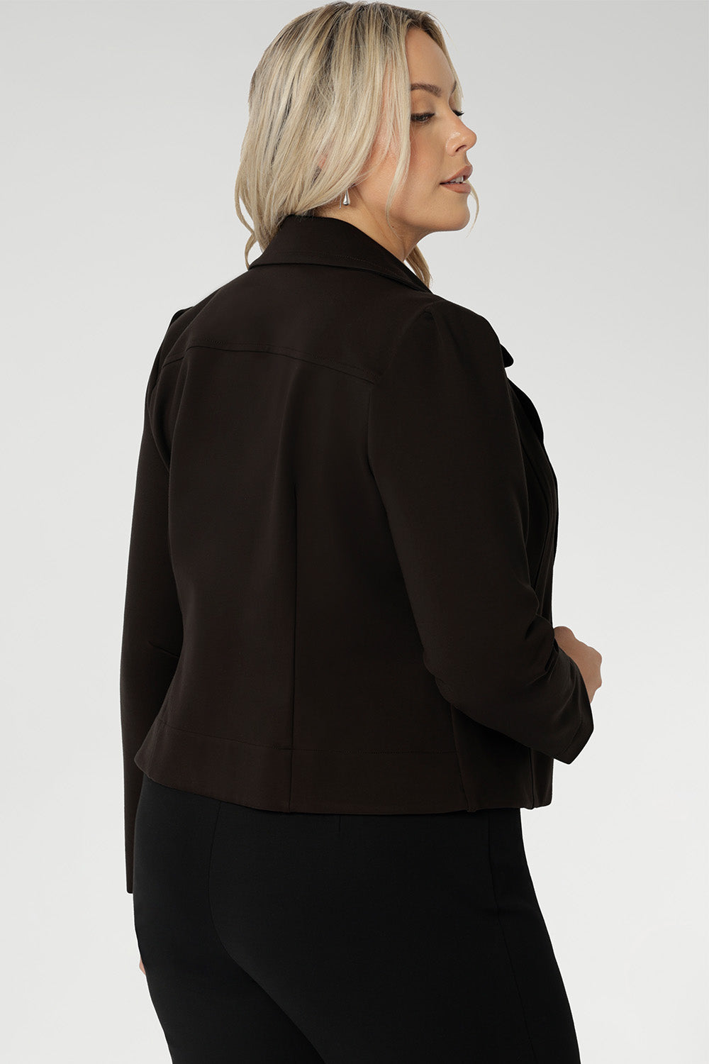 Its contemporary design features a clean front with double-layered tailored panels, complemented by refined collar and notch lapels with subtle topstitch detailing for a polished finish. A shoulder yoke and back darts enhance the fit, while full-length sleeves with gentle tucks at the sleeve heads add a touch of softness to the overall look.