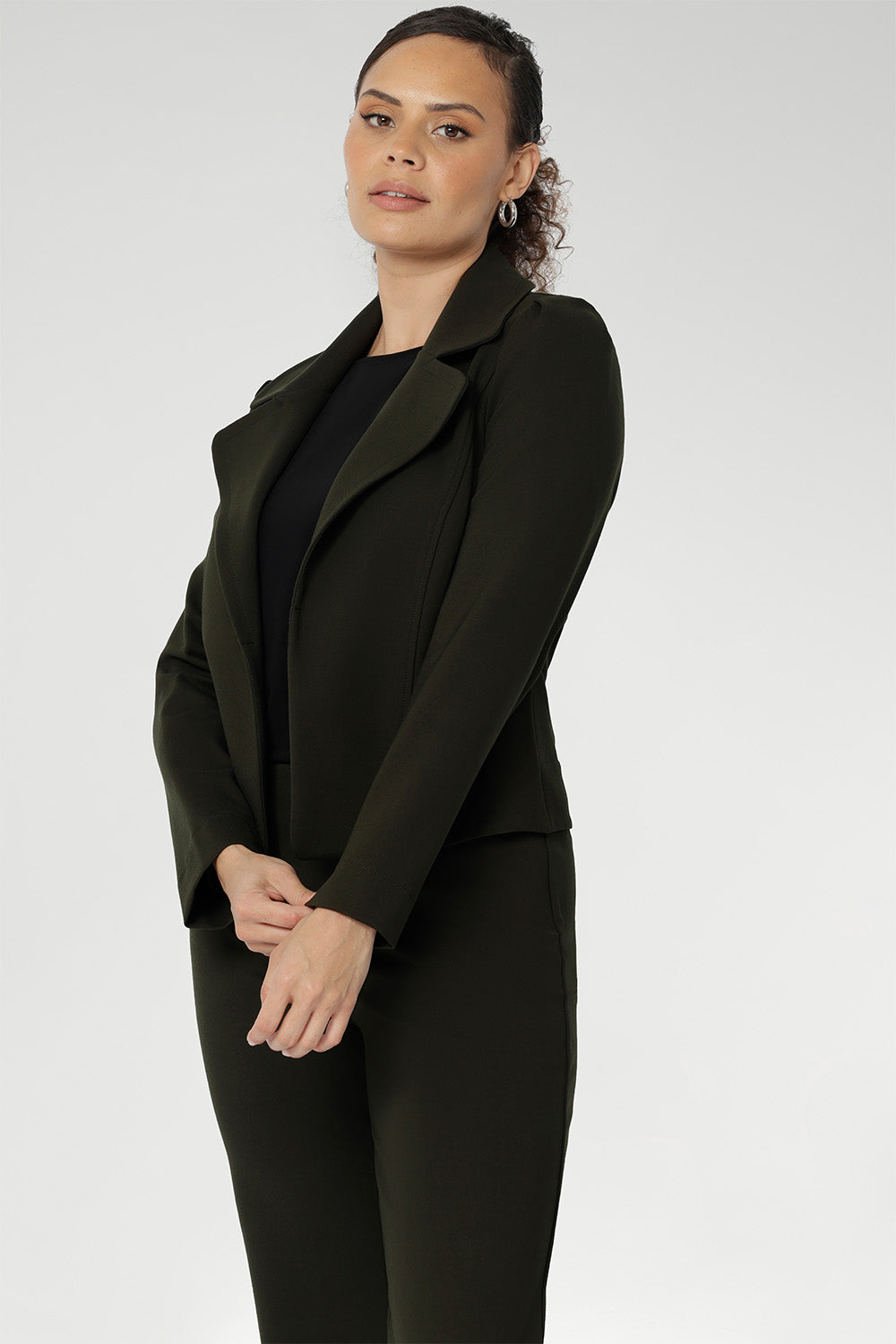 The cropped silhouette is complemented by double-layered front panels and refined collar and notch lapels, finished with subtle topstitch detailing for a sophisticated edge. A structured shoulder yoke and back darts create a flattering, contoured fit.