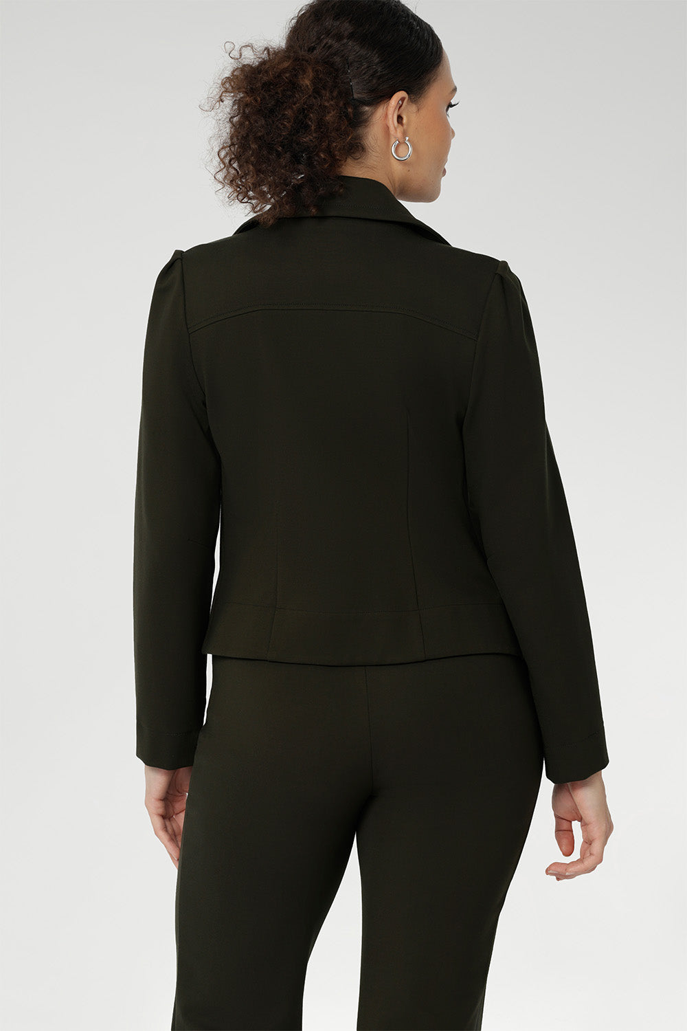 The cropped silhouette is complemented by double-layered front panels and refined collar and notch lapels, finished with subtle topstitch detailing for a sophisticated edge. A structured shoulder yoke and back darts create a flattering, contoured fit, while the full-length sleeves with gentle tucks at the sleeve heads offer a soft, elegant finish.