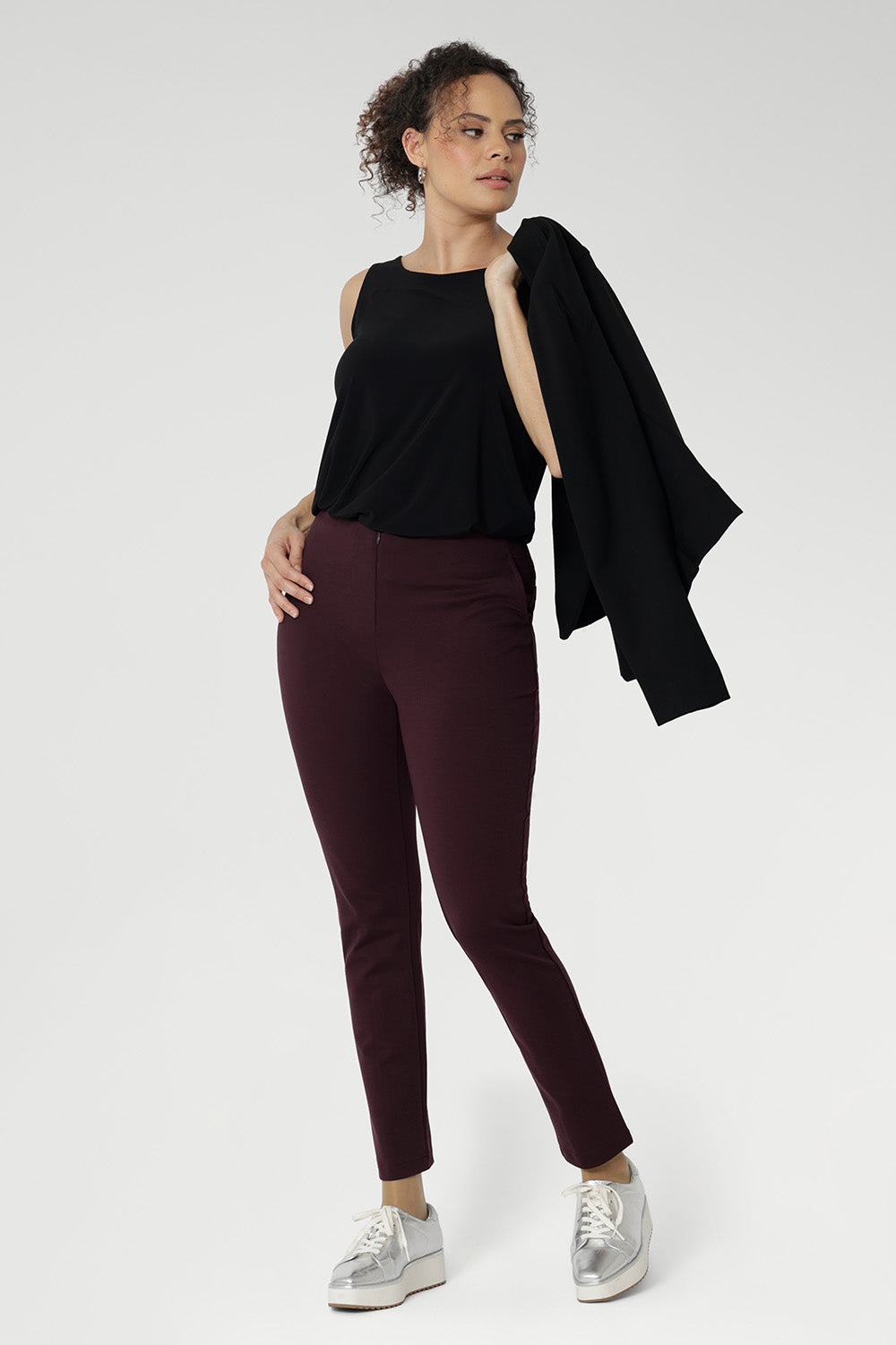 Versatility with the Harlee Reversible Top—a must-have essential that effortlessly blends comfort, style, and practicality. Crafted from our signature dry-touch stretch jersey, this everyday piece features a chic boat neckline and a sleek, streamlined silhouette. Over 30's woman wears her cami tucked into wine coloured skinny leg pants and sneakers.