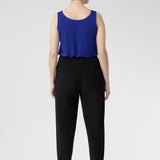 The Indi Pant combines comfort and style in a sleek, tapered silhouette. Made from lightweight black dry-touch jersey with stretch, it features a mid-rise pull-on fit, front gathers, and ankle cuffs with tuck detail. Easy to dress up with a blazer or wear casually for travel days. Available in two heights.