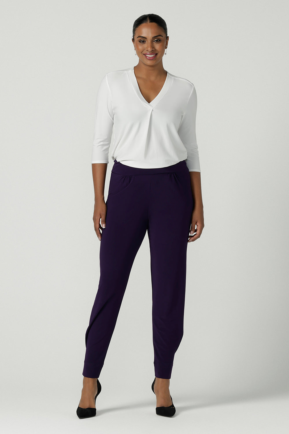 A size 10 woman wears the Indi Pant in Amethyst. An Indi pant in amethyst with a mid rise waistband, tapered ankle balloon leg style. A made in Australia pant for women. Perfect travel friendly non-crease pant. Size 8-10.