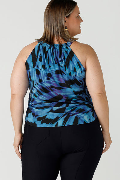Back view of Curvy woman wearing a size 18 tie neck tie top Iris in Flutter with a blue digital print. Size inclusive clothes for women size 8 - 24. Digital blue and purple print. Made in Australia. Styled back with navy slim fit Brooklyn pant.