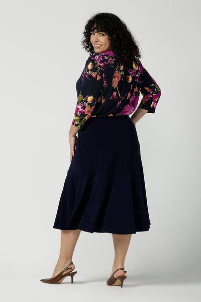 Back view of a size 18 woman wears the Jaime Top in Celeste. A comfortable workwear top that is easy care jersey. Featuring 3/4 sleeves and a v-neckline. Made in Australia and size inclusive. Size 8 - 24. Styled back with the Berit Skirt in Navy.