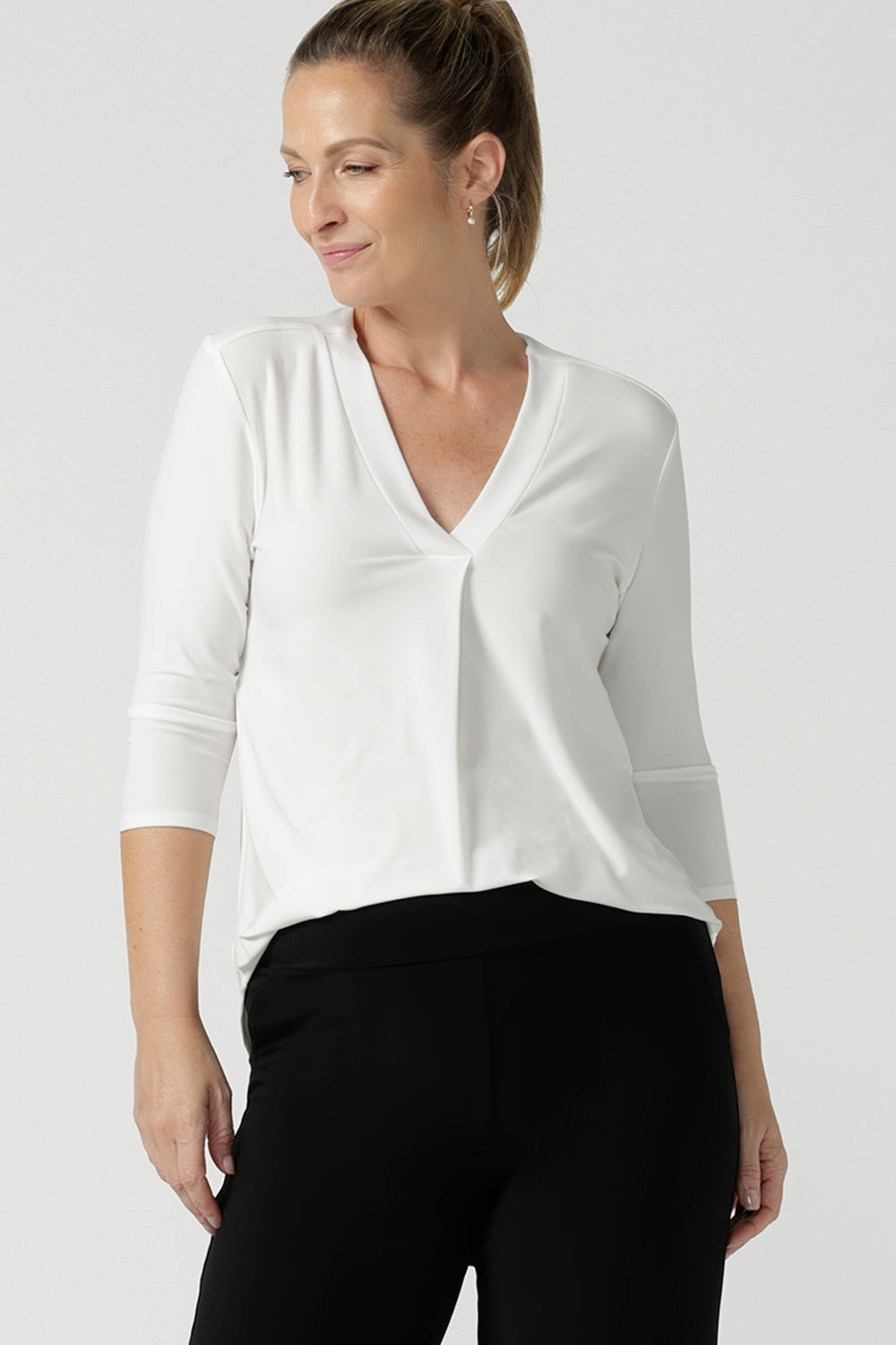 A size 10 woman wears the Jaime top in Vanilla. A comfortable workwear top for women in soft dry touch easy care versey. Featuring a v-neck with pleat front and bind. 3/4 sleeve and made in Australia for women size 8 - 24. 