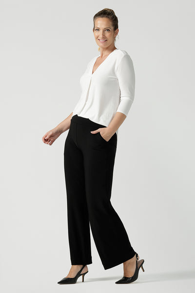 A size 10 woman wears the Jaime top in Vanilla. A comfortable workwear top for women in soft dry touch easy care versey. Featuring a v-neck with pleat front and bind. 3/4 sleeve and made in Australia for women size 8 - 24. Styled back with Black Monroe pants.