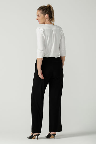 Back view of a size 10 woman wears the Jaime top in Vanilla. A comfortable workwear top for women in soft dry touch easy care versey. Featuring a v-neck with pleat front and bind. 3/4 sleeve and made in Australia for women size 8 - 24. Styled back with Black Monroe pants.