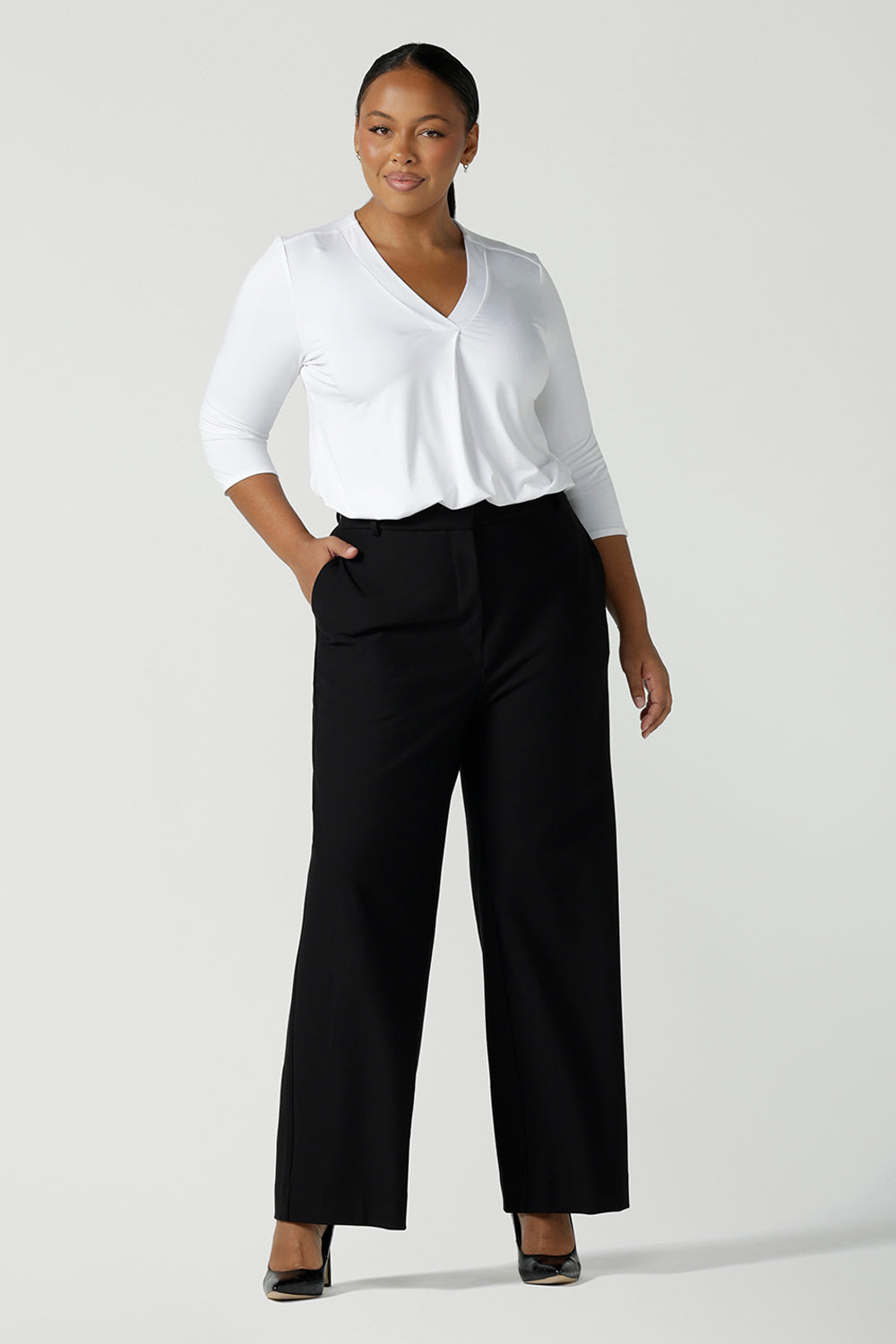 A size 16 curvy women wears the Kade pant in Black. A high waist pant in technical stretch ponte. High waisted design with belt loops, pockets and fly front detail. Made in Australia for women size 8 - 24.
