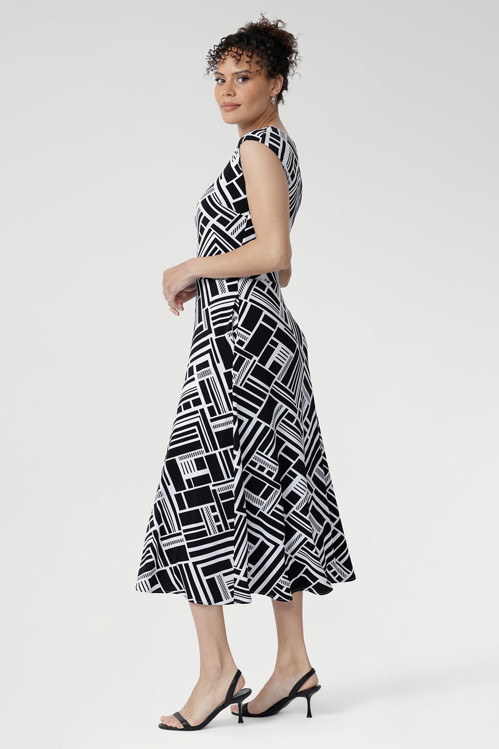 The Janine Dress in Moderno is a beautifully tailored fit-and-flare midi dress crafted from our signature high-quality, dry-touch jersey, designed to offer both elegance and comfort for any occasion. Featuring a bold geometric print in classic black and white.