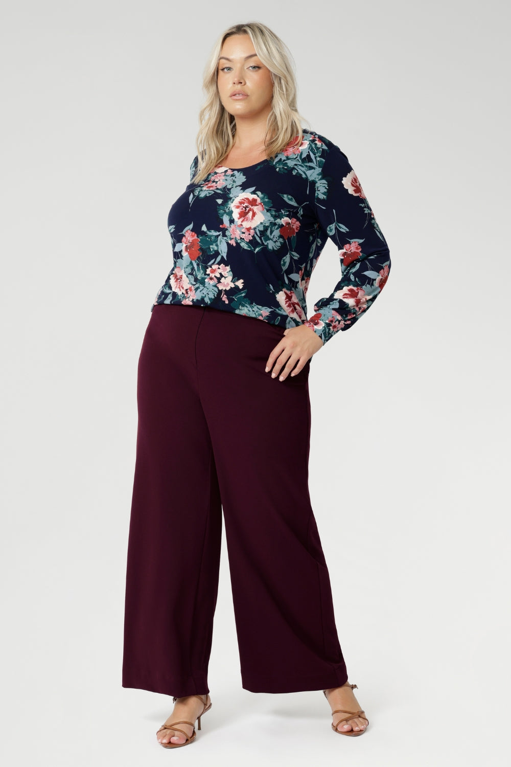 Feminine, flattering, and thoughtfully designed, the Jasper Top in Vintage Rose is a versatile staple made to elevate your everyday style. Plus size woman wears her Jasper Top tucked into wine coloured trousers.