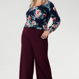 Feminine, flattering, and thoughtfully designed, the Jasper Top in Vintage Rose is a versatile staple made to elevate your everyday style. Plus size woman wears her Jasper Top tucked into wine coloured trousers.