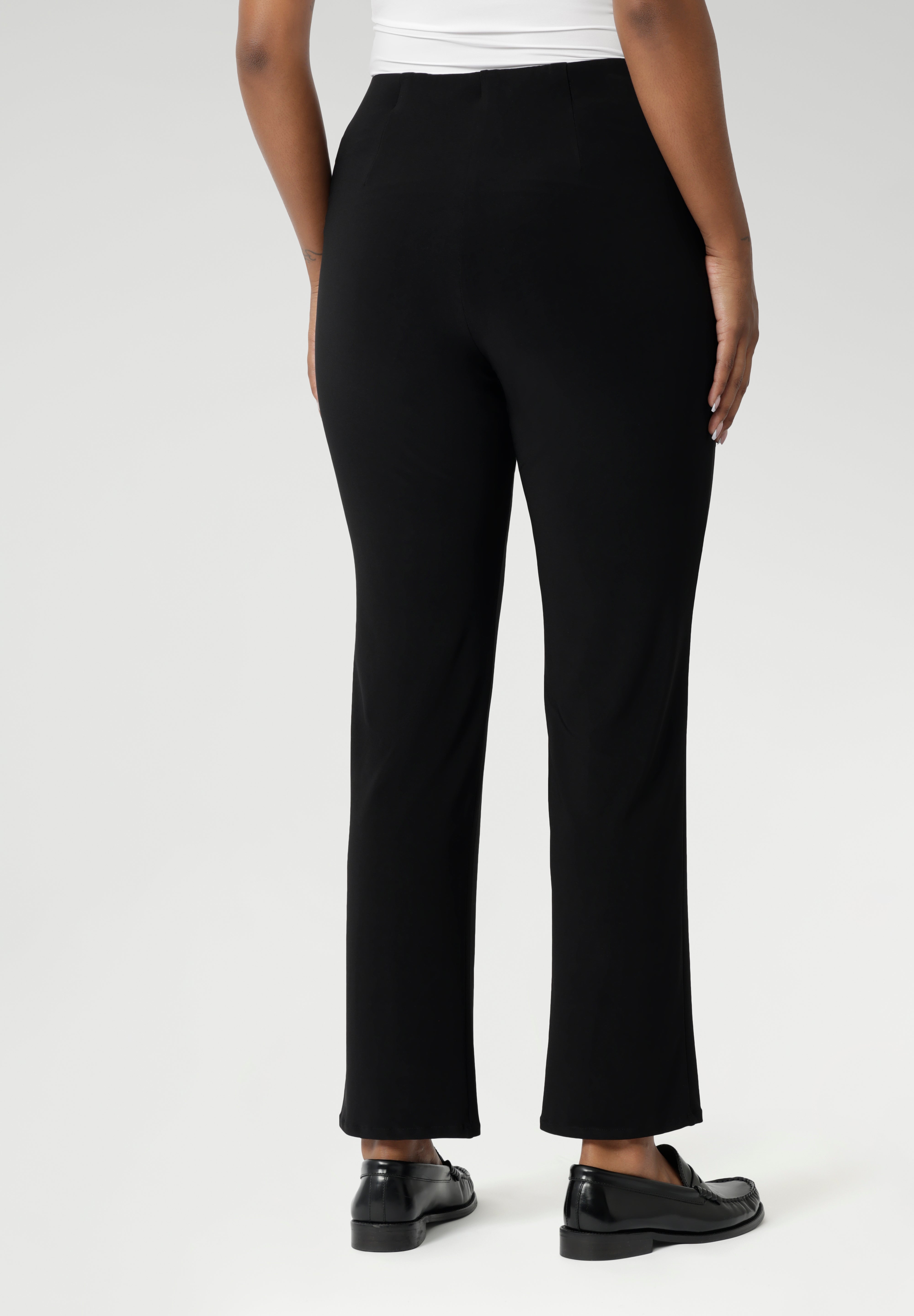 Size 10 model pairs black pants with white top & black loafers for a casual look.