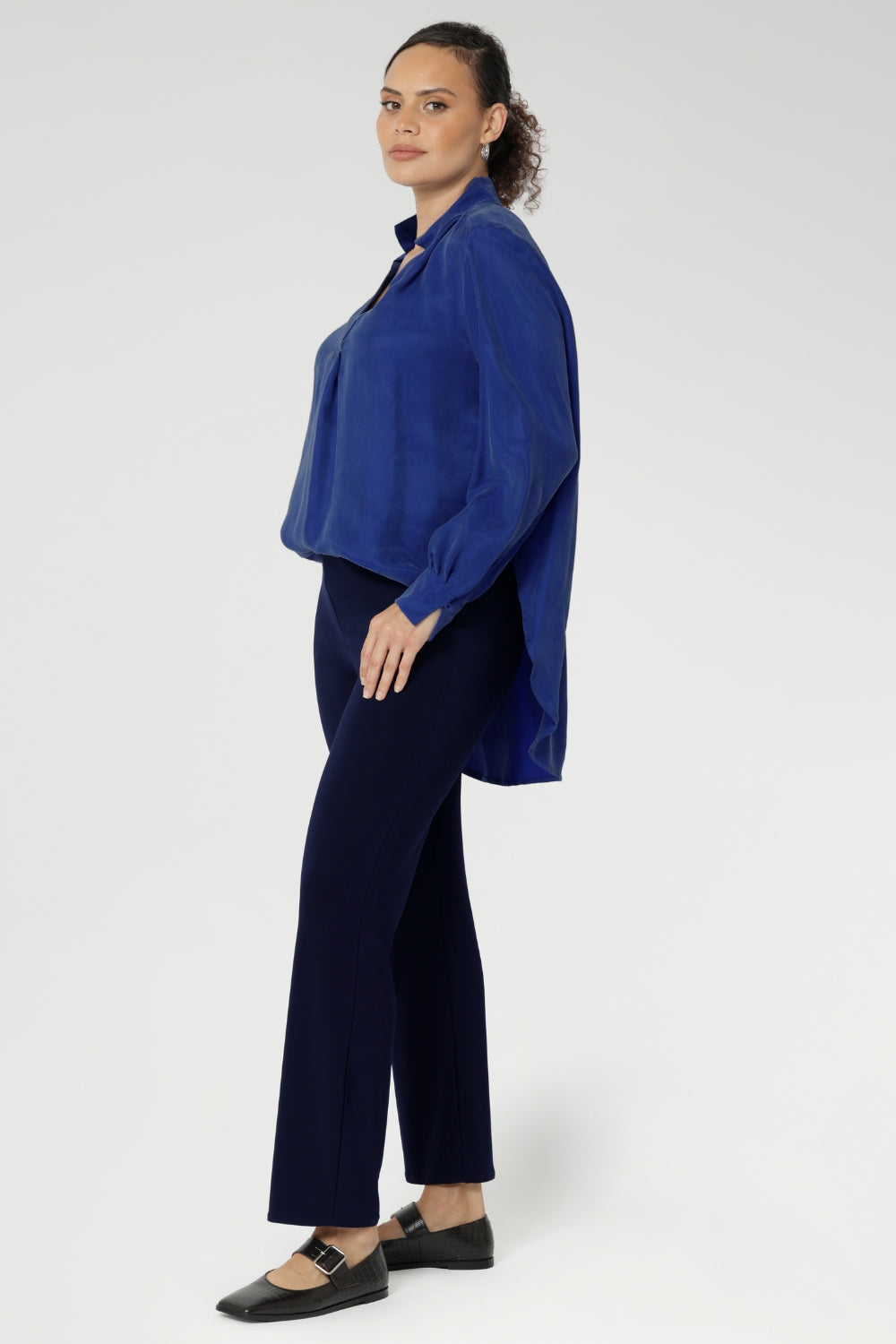 The ideal workwear pant for the combination of comfort, style, and ease. Size 10 woman wears navy workwear pants with long cobalt blouse and brown ballet flats.