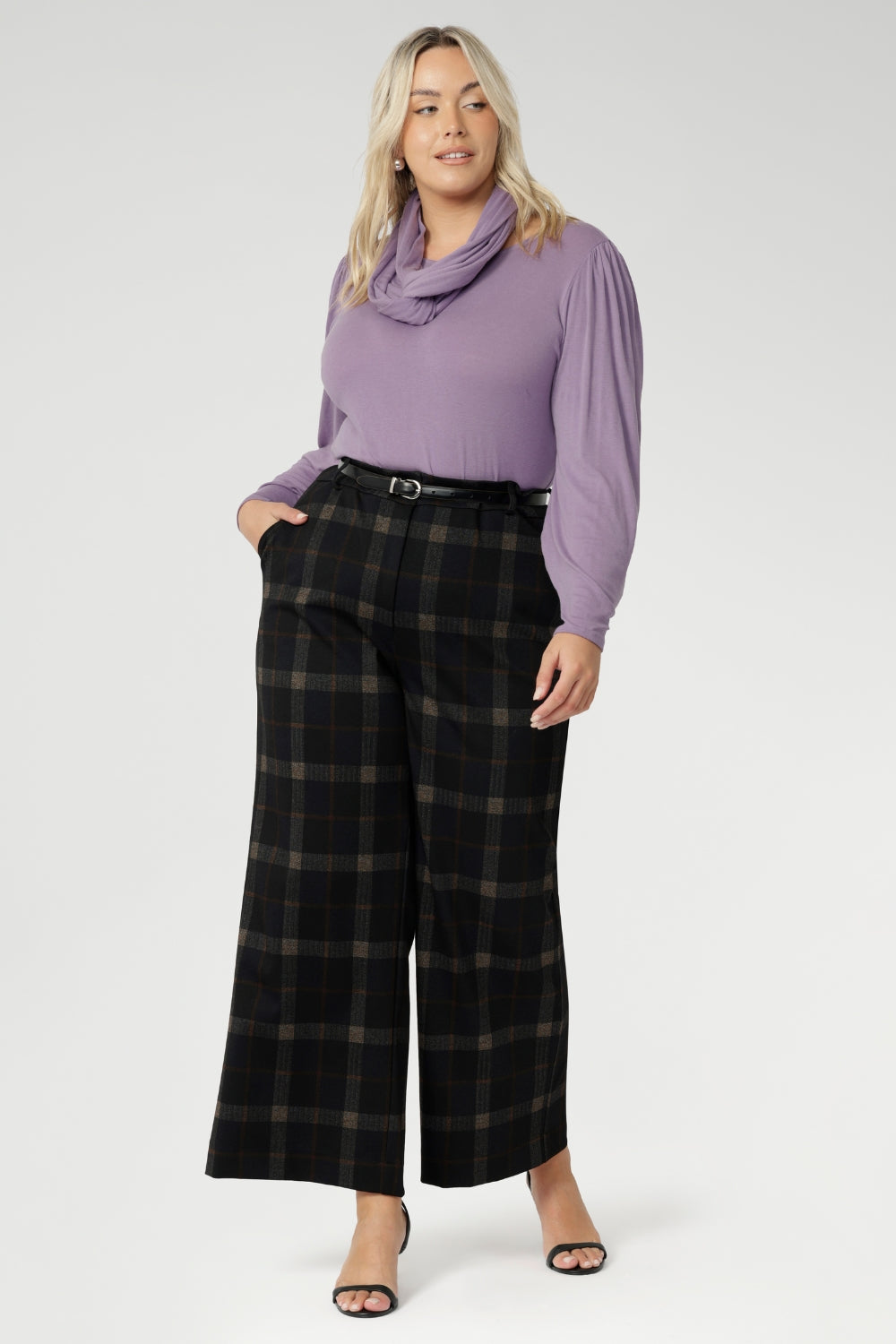 Designed to move with you, this collection offers refined silhouettes that transition effortlessly from work to smart-casual settings. Plus size woman wears her Kade wide leg pants with Lilac coloured top and scarf & black kitten heels.