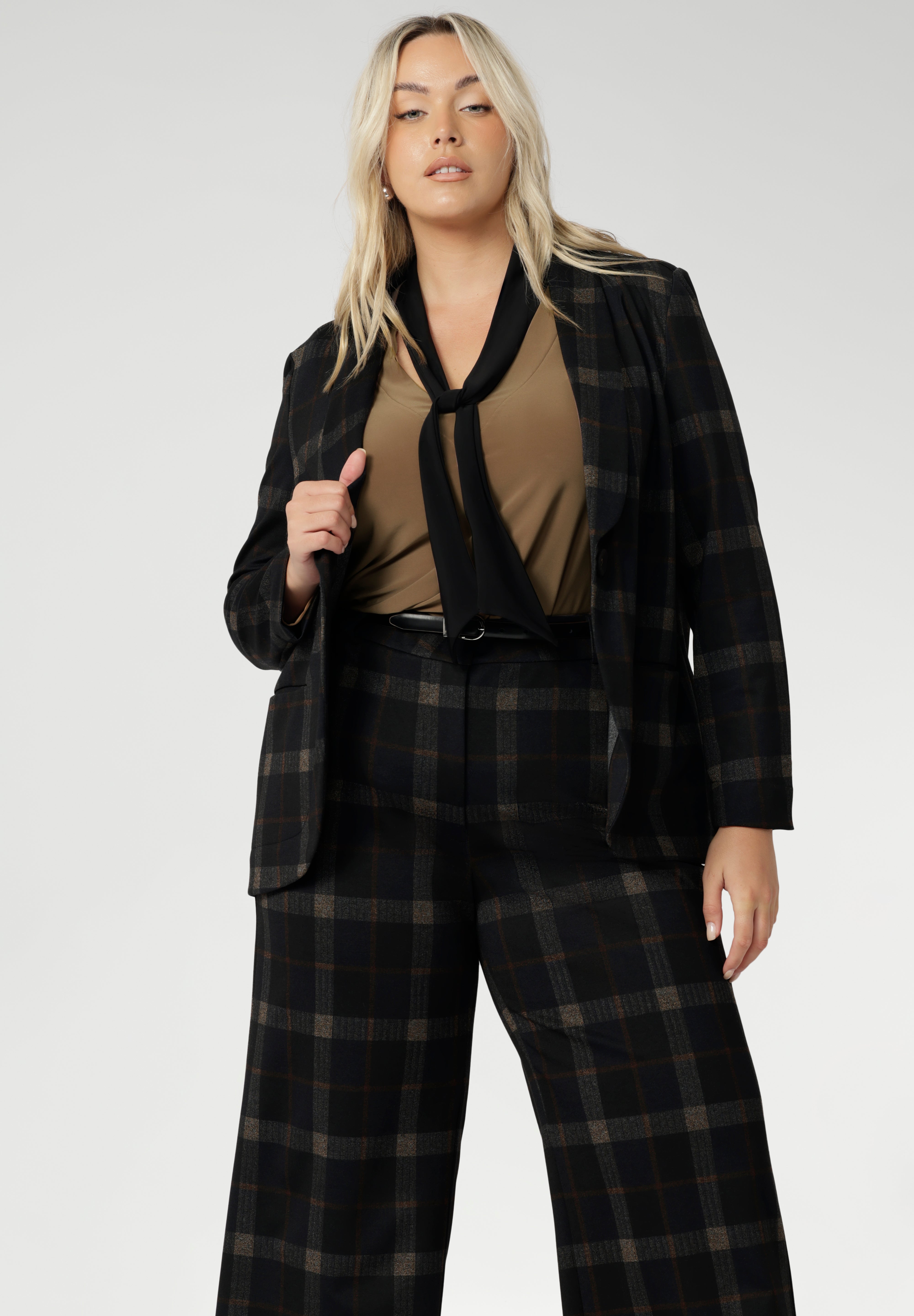 Designed for women who want style that works across occasions, this jersey top blends comfort with quiet sophistication. The soft V-neckline is accented by attached neck ties in a warm coffee tone, offering styling versatility. Plus zie woman wears her neck tie top under plaid suit set with matching blazer and wide leg pants.