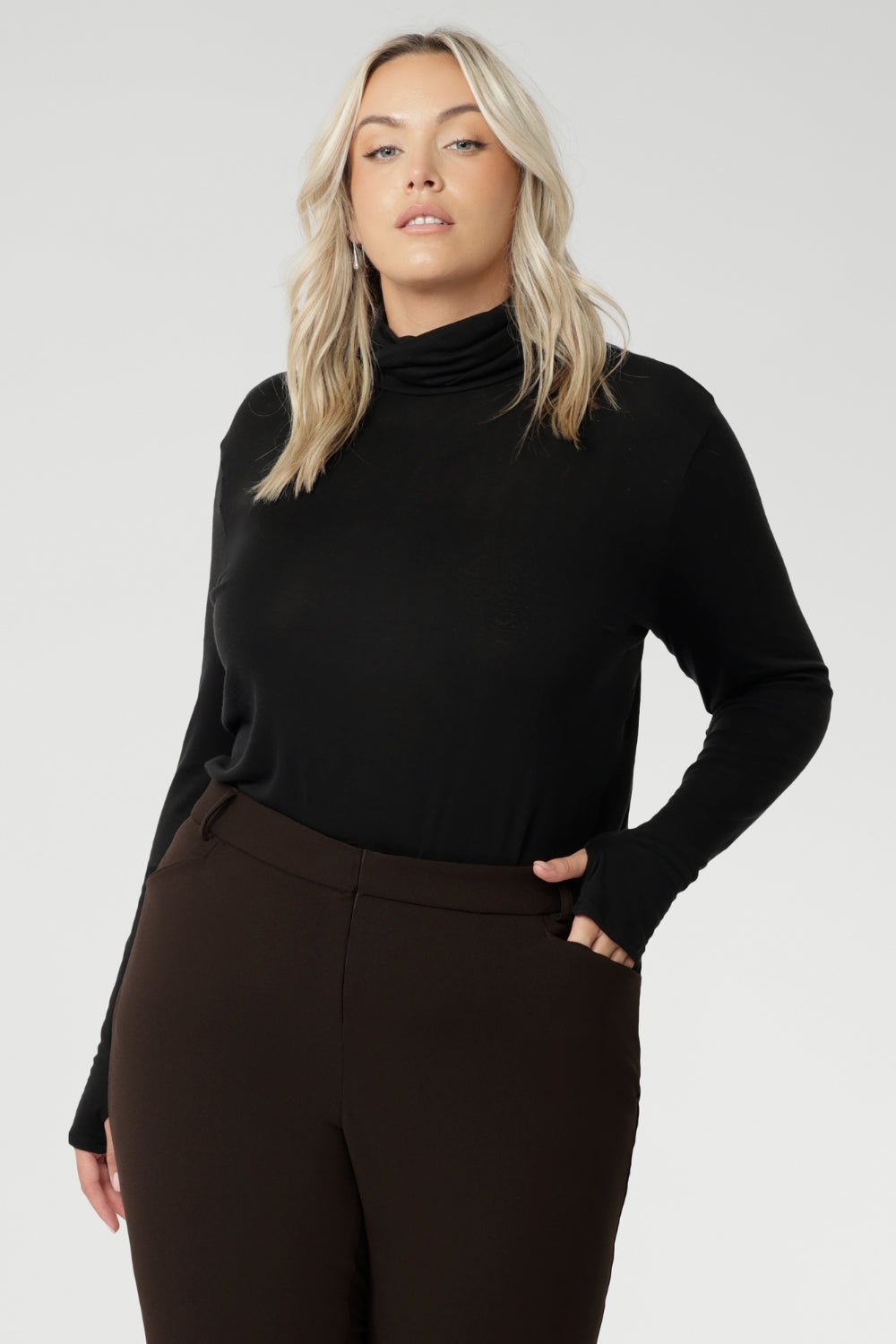 This black long-sleeve top is crafted from a luxurious blend of lightweight TENCEL™ and wool, offering breathable warmth without the bulk. The high turtleneck adds a cosy, refined touch, while built-in thumb holes provide extra coverage and comfort on cooler days.