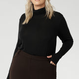 This black long-sleeve top is crafted from a luxurious blend of lightweight TENCEL™ and wool, offering breathable warmth without the bulk. The high turtleneck adds a cosy, refined touch, while built-in thumb holes provide extra coverage and comfort on cooler days.