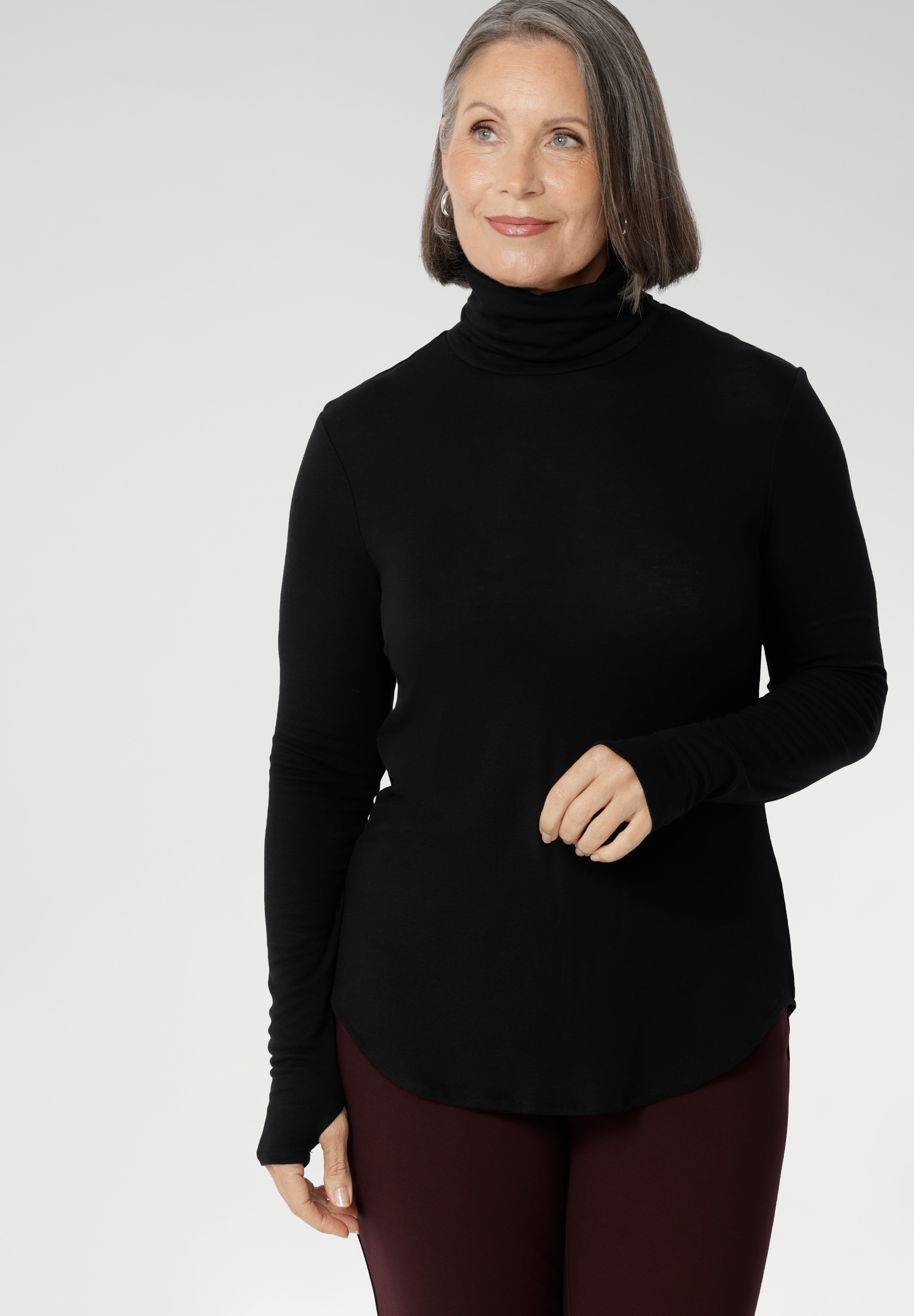This Black long-sleeve top is crafted from a luxurious blend of lightweight TENCEL™ and wool, offering breathable warmth without the bulk. The high turtleneck adds a cosy, refined touch, while built-in thumb holes provide extra coverage and comfort on cooler days.