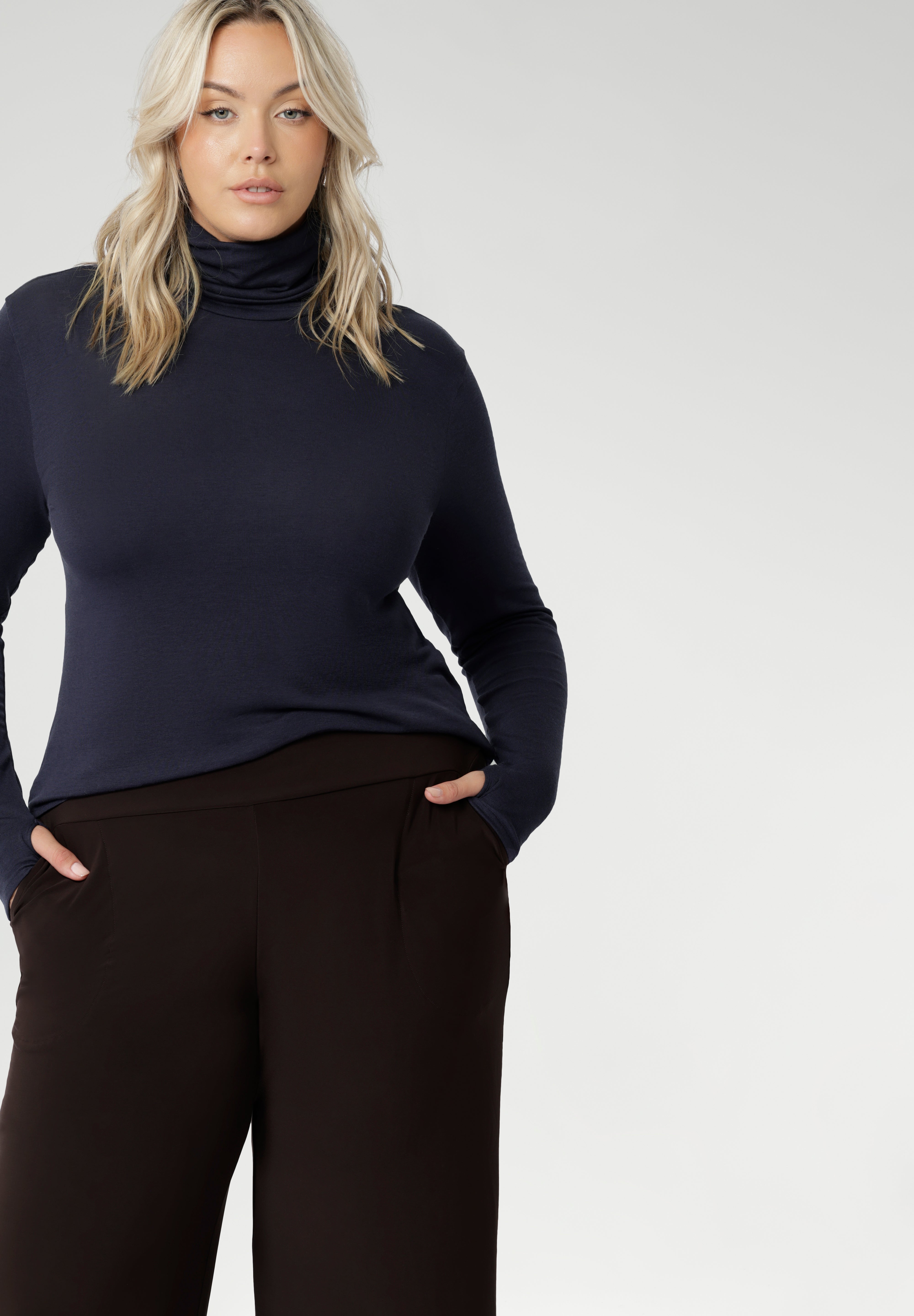 Size 18 woman wears long-sleeved top that features convenient thumb holes for added comfort and warmth and a high turtle neck. Crafted from lightweight, warm tencel wool fabric and in sizes 8-24.