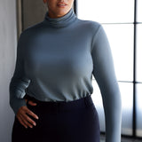 Introducing the Kean high turtleneck top from the Light Layers collection, a stylish and functional piece designed to elevate your wardrobe as the seasons cool. This long-sleeved top features convenient thumb holes for added comfort and warmth. Made from a blend of stretchy Tencel wool fabric, it offers both flexibility and coziness, making it the perfect layering piece for cooler weather.