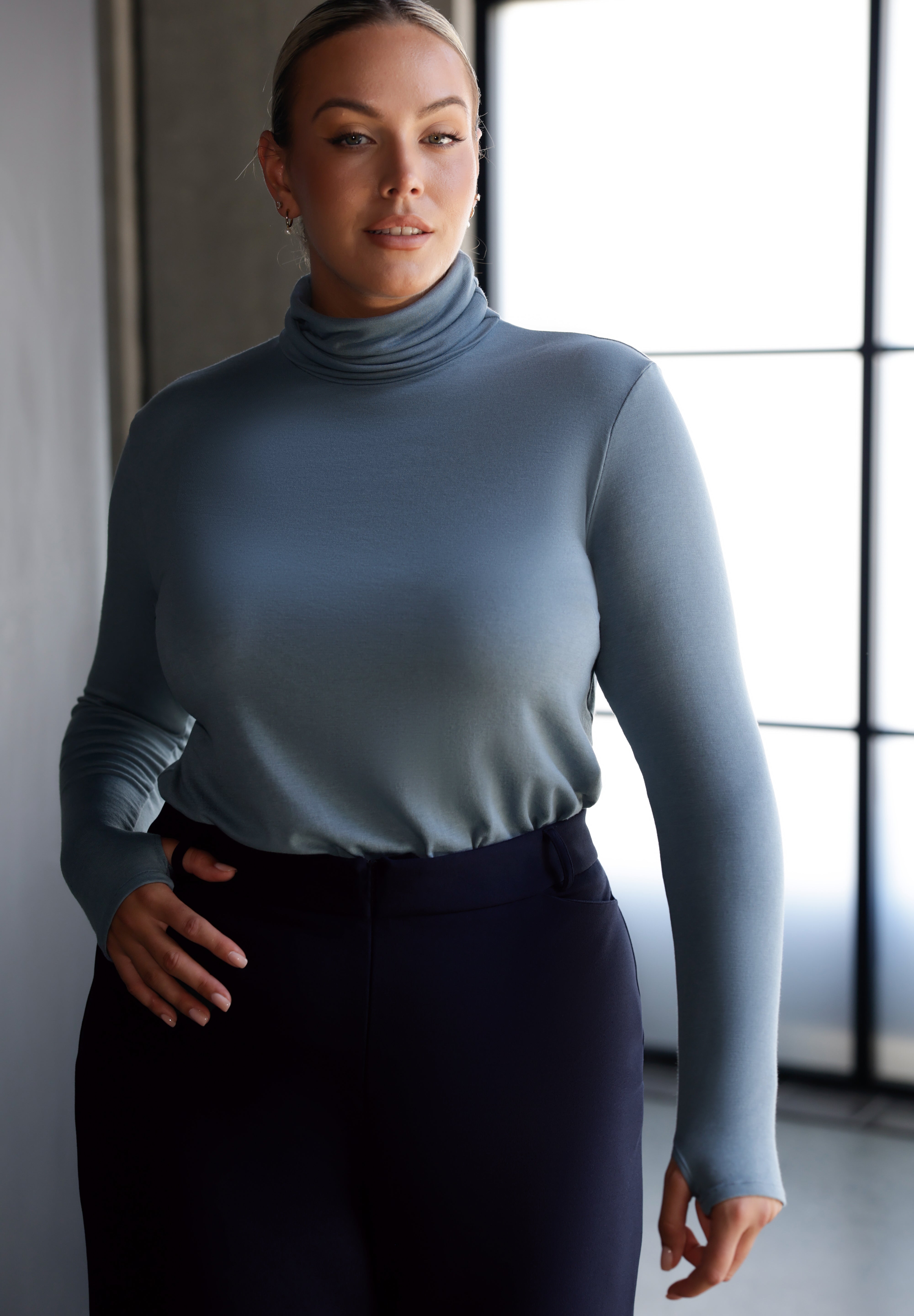 Introducing the Kean high turtleneck top from the Light Layers collection, a stylish and functional piece designed to elevate your wardrobe as the seasons cool. This long-sleeved top features convenient thumb holes for added comfort and warmth. Made from a blend of stretchy Tencel wool fabric, it offers both flexibility and coziness, making it the perfect layering piece for cooler weather.