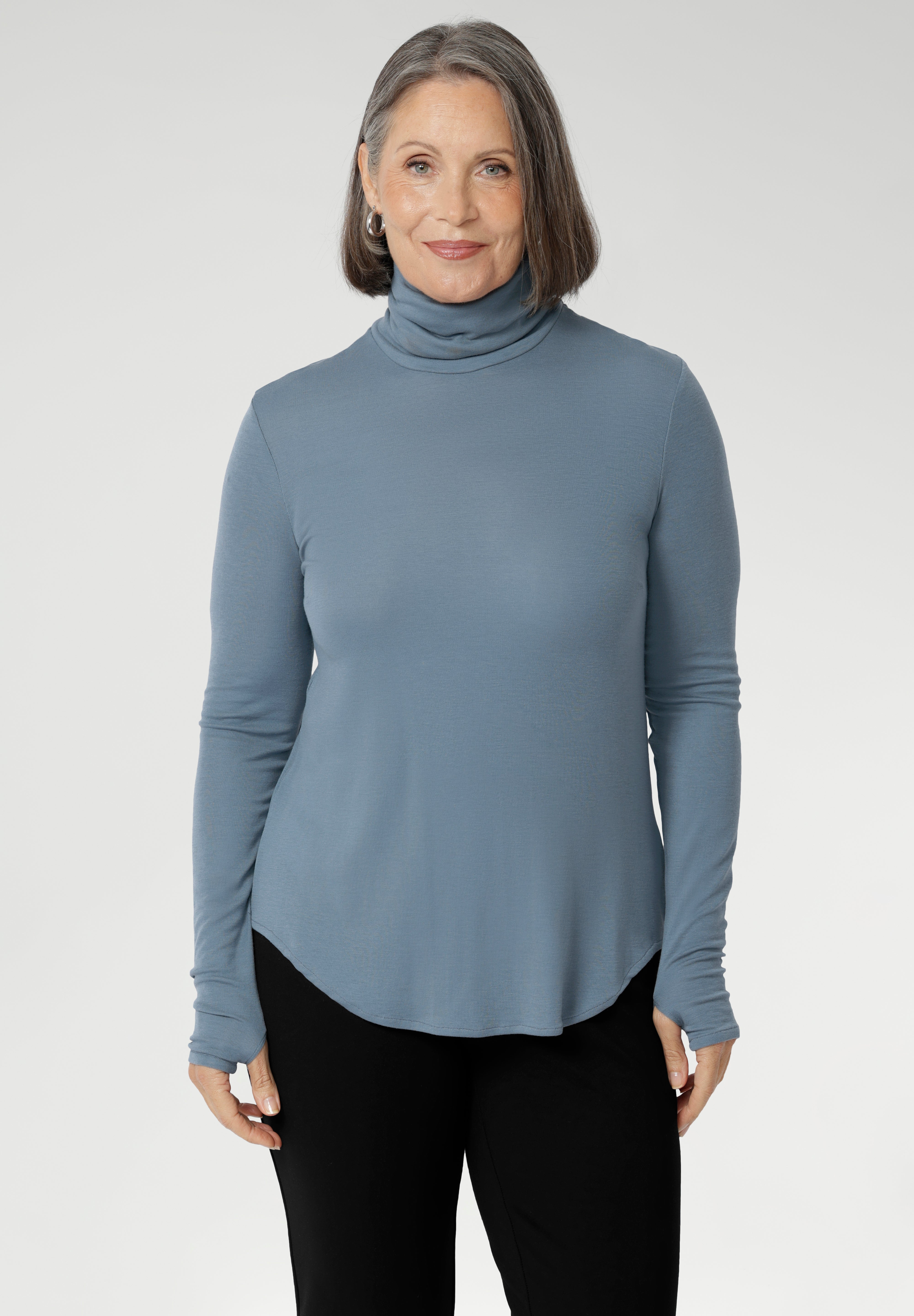 Introducing the Kean high turtleneck top from the Light Layers collection, a stylish and functional piece designed to elevate your wardrobe as the seasons cool. This long-sleeved top features convenient thumb holes for added comfort and warmth. Made from a blend of stretchy Tencel wool fabric, it offers both flexibility and coziness, making it the perfect layering piece for cooler weather.