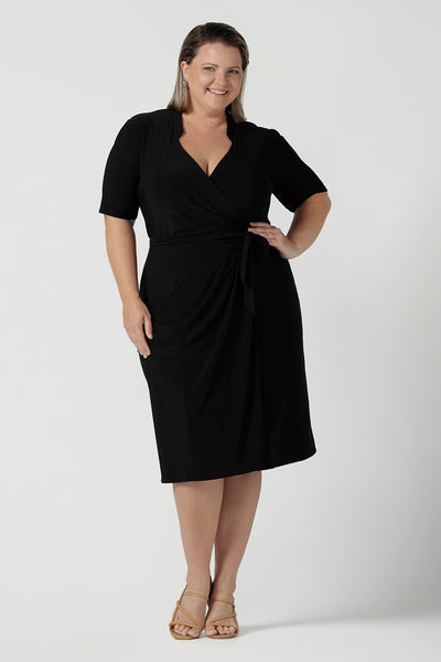 A size 18 woman wears the Kris dress in black. A functioning wrap work dress in soft black jersey. Great for being comfortable in the office. Made in Australia for women size inclusive fashion 8 - 24.
