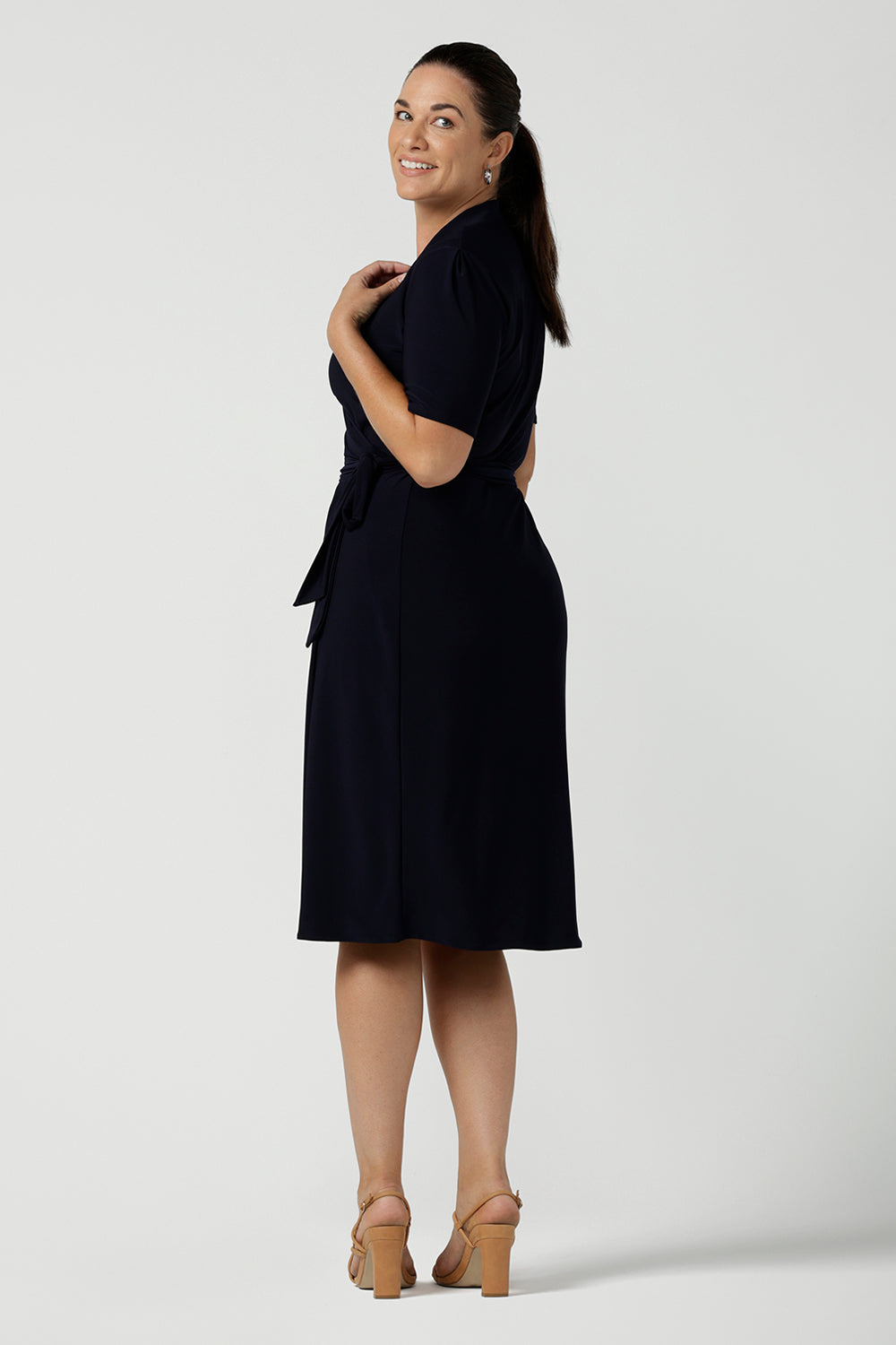 Side view of a Kade dress in Navy is a functioning wrap dress in navy. Featuring a mandarin collar and short sleeves. Gathered at the waist with a functioning tie. Made in Australia for women size 8 - 24.