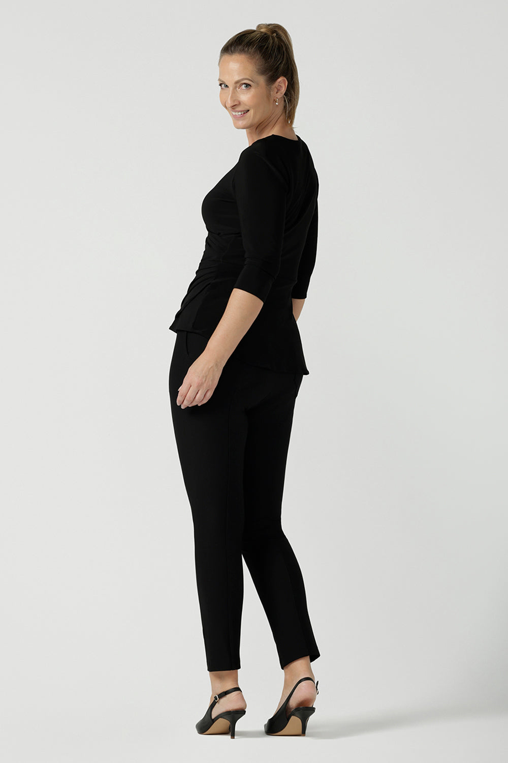 Back view of a size 10 woman wears the Kyle top in Black soft jersey. A soft wrap top made in Australia for women size 8 - 24. The perfect work to weekend top in comfortable and easy care jersey. Made in Australia for women size 8 - 24.
