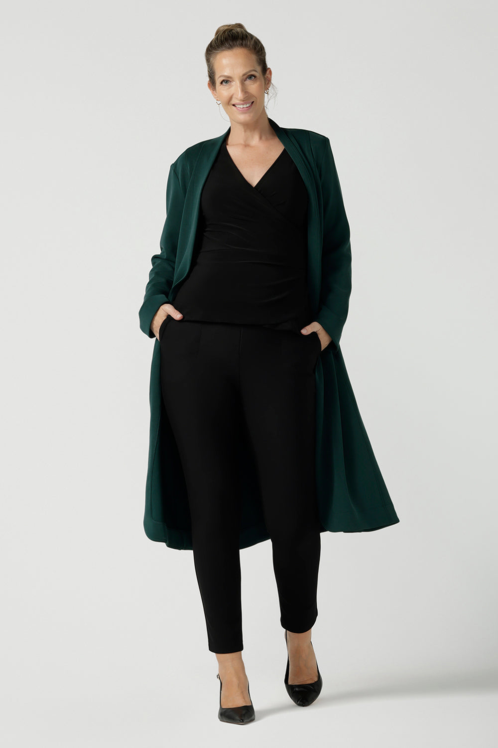 Back view of a size 10 woman wears the Kyle top in Black soft jersey. A soft wrap top made in Australia for women size 8 - 24. The perfect work to weekend top in comfortable and easy care jersey. Made in Australia for women size 8 - 24. Styled back with the Sorel Trenchcoat in Alpine. 