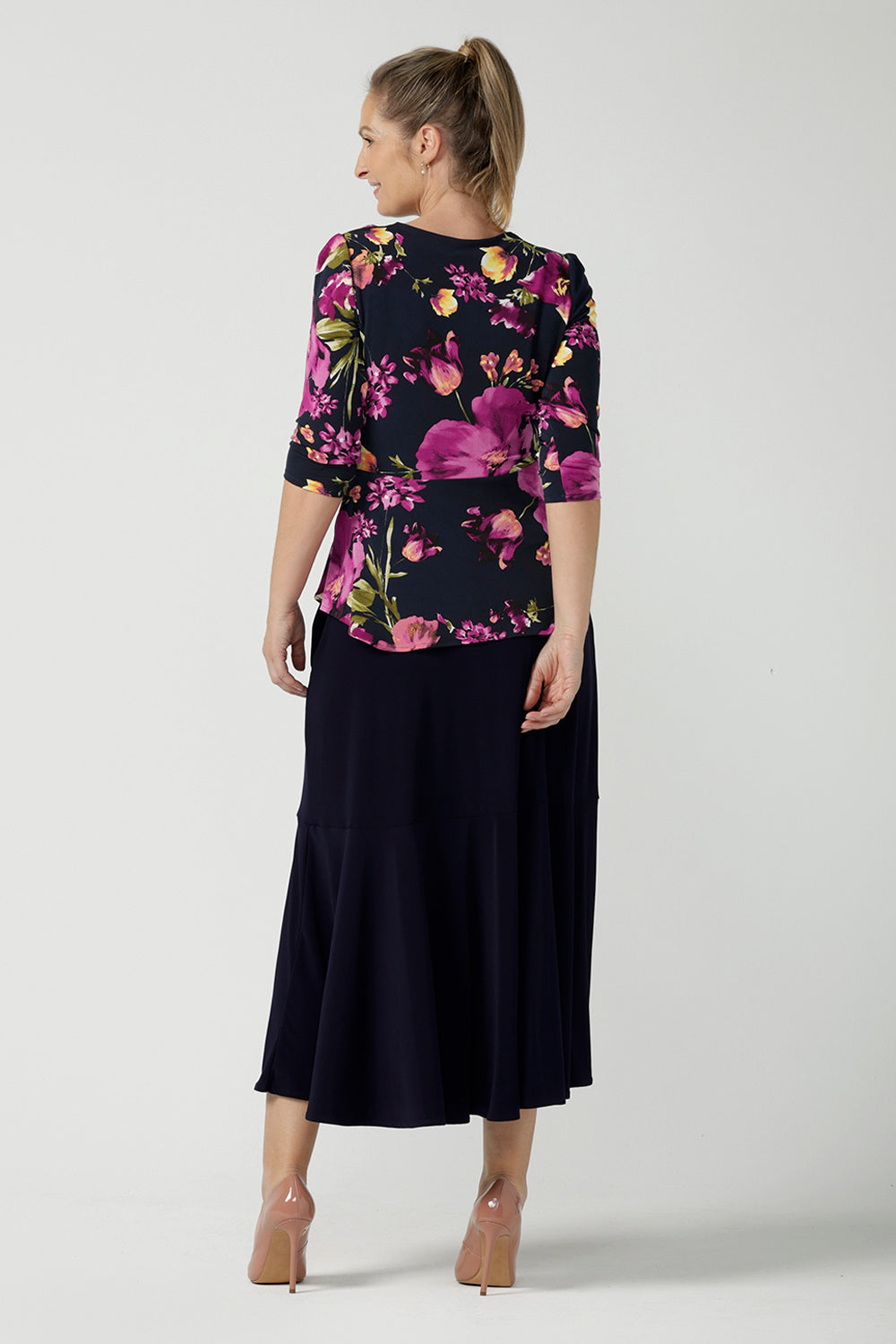 Back view of a size 10 woman wears the Celeste Top and Navy Berit Maxi Skirt. A beautiful fixed wrap top with a peplum and shoulder sleeeve tuck with 3/4 sleeves. Made in Australia for women size 8 - 24.