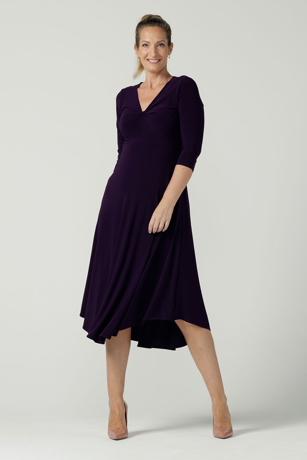 Size 10 Woman wears the Amethyst Kyra dress in jersey. Made in Australia for women. Beautiful twist front neckline with 3/4 sleeve, high-low hem, empire line. Work wear for women and easy care. Great wedding guest outfit, mother of the bride. Made in Australia for women size 8 - 24.