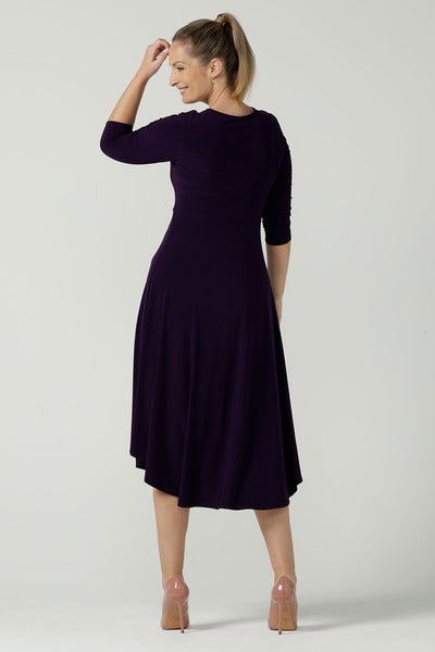 Back view of a size 10 Woman wears the Amethyst Kyra dress in jersey. Made in Australia for women. Beautiful twist front neckline with 3/4 sleeve, high-low hem, empire line. Work wear for women and easy care. Great wedding guest outfit, mother of the bride. Made in Australia for women size 8 - 24.