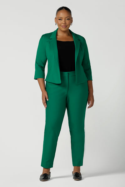 A plus size 18 woman wears a tailored jacket with open front and collar and notch lapels is made in Emerald green ponte fabric. Styled with Emerald green tailored pants, and a black top for a stylish workwear look. Shop exclusive luxury, this work jacket is available at Australian and New Zealand women's clothing label, L&F.